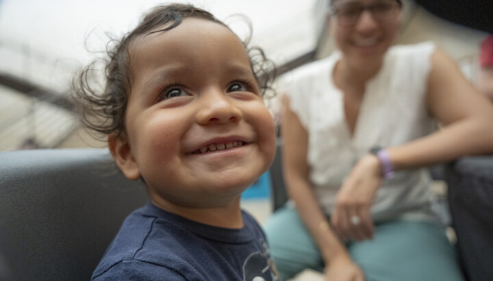 A smiling medium-skinned toddler-aged child plays in the Carter's Atrium.