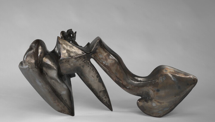 An abstract welded steel sculpture; its organic form has three "legs" that it rests on.