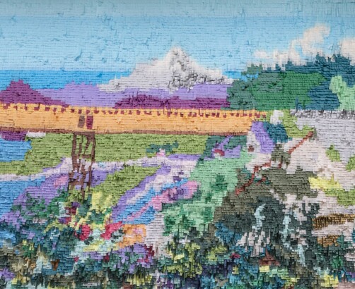 Mountain and bridge made out of colored tissue paper arranged like paint on a wall 