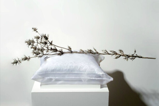 A sculpture of a white pillow with a dead branch of clover flowers.