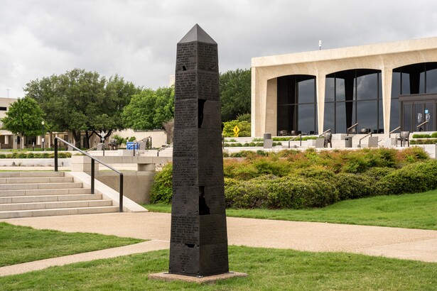 A bronze obelisk with fragments of text covering each side stands outside on the Carter grounds.