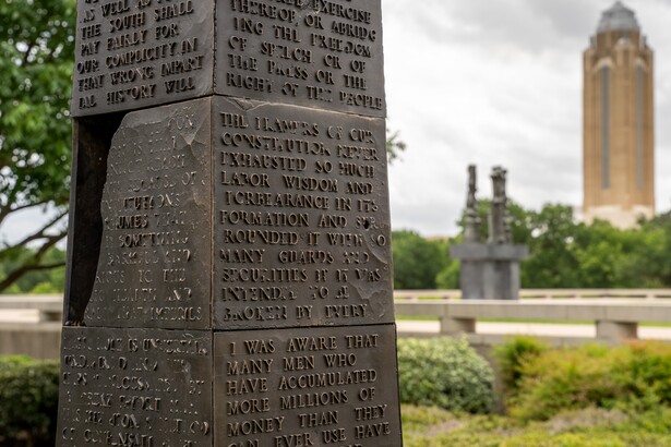 A detail of a bronze obelisk with fragments of text covering each side.
