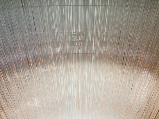A detail of a sculpture that is made up of thousands of clear, glass threads.