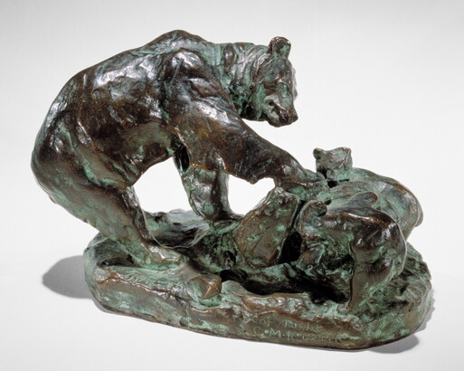 A bronze sculpture of a bear and its cub pawing an upturned rock.