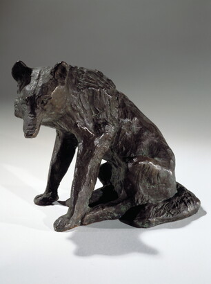 A bronze sculpture of a sitting coyote.
