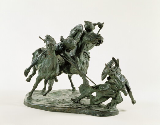 A bronze sculpture of two horses in mid-gallop, with both riders lunging toward a crouching man behind a shield.