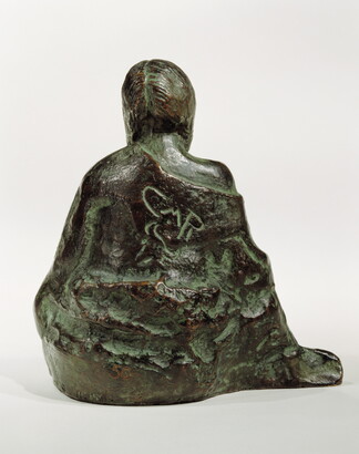 A bronze sculpture of a seated Native American person wrapped in a robe.