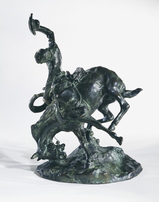 A bronze sculpture of a cowboy trying to ride a bucking horse.