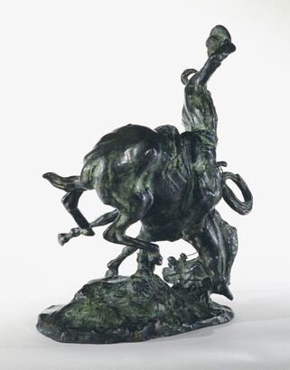 A bronze sculpture of a cowboy trying to ride a bucking horse.