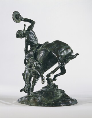 A bronze sculpture of a cowboy trying to ride a bucking horse.
