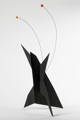 A black, metal, star-like shaped sculpture with two wires rising from the top, one capped with a yellow circle and the other with an orange circle.