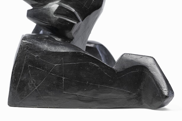 An abstract, black sculpture resembling a figure&#039;s head and shoulders.