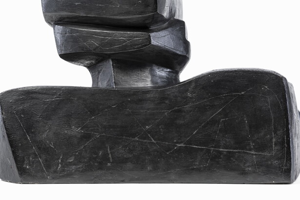 An abstract, black sculpture resembling a figure&#039;s head and shoulders.