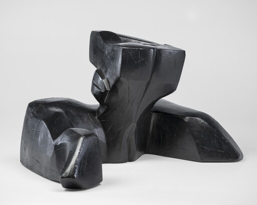 An abstract, black sculpture resembling a figure&#039;s head and shoulders.
