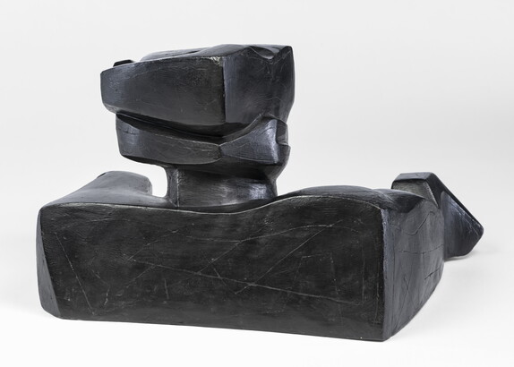 An abstract, black sculpture resembling a figure&#039;s head and shoulders.