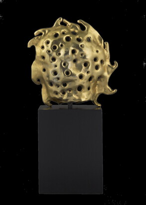 A bronze sculpture of a gold sun sitting atop a tall, dark rectangular base.
