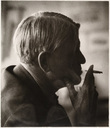 A sepia-toned photograph of a man's head in profile holding a cigarette posed in front of his lips.