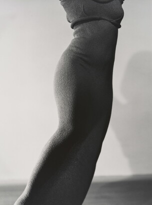 A black-and-white photograph of a slim, feminine torso wearing a form-fitting, knit dress.