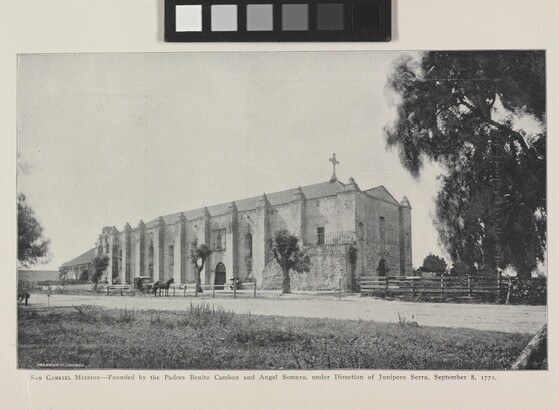 A black-and-white photograph of a mission church by a dirt road.