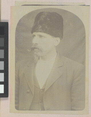 A faded sepia-toned portrait of a White man with a handlebar moustache wearing a fur Cossack-stye hat and a three-piece suit.