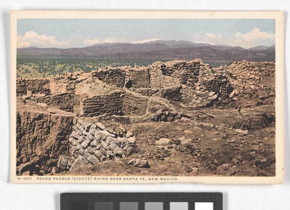 A color postcard of a ruined, stone building with multiple rooms in a mountainous landscape.