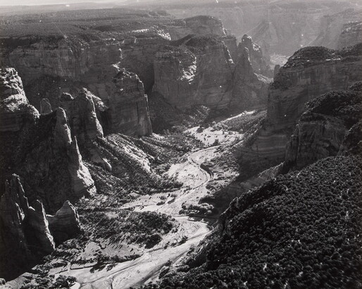 A black-and-white photograph of a landscape with two sides of steep and rocky cliffs and a dry valley between them.