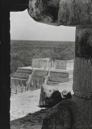 A black-and-white photograph of an ancient step pyramid viewed through a stone window.