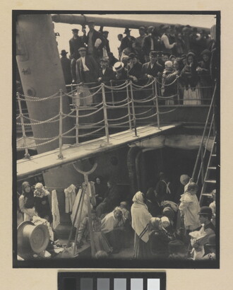 A black-and-white photograph of people outside on two decks of a crowded ship.