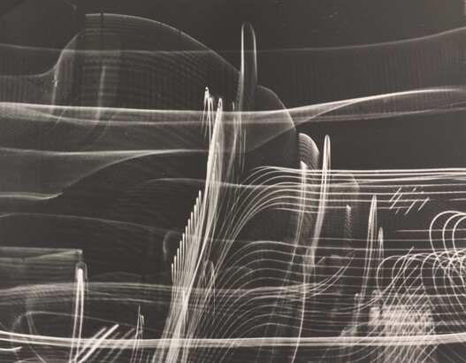 A black-and-white photograph of abstract streaks of white light swirling horizontally and vertically on a black background.