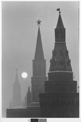 A black-and-white photograph of three spires fading into the distance with a bright, full moon rising.