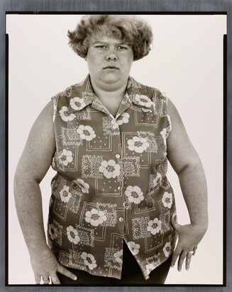 A black-and-white portrait photograph of a White woman with short hair in a sleeveless button-down shirt with a floral pattern.