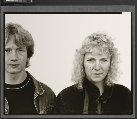 A black-and-white portrait photograph of a young White man with shaggy hair wearing a jean jacket, and a young White woman with curly hair wearing a corduroy jacket.