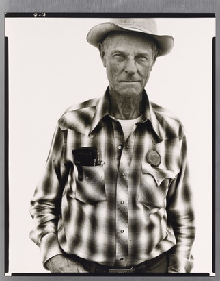 A black-and-white portrait photograph of an older White man wearing a plaid, button-down shirt and western hat.