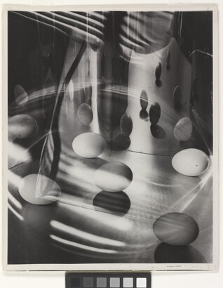 A black-and-white photograph of eggs surrounded by light, shadows, and reflections.