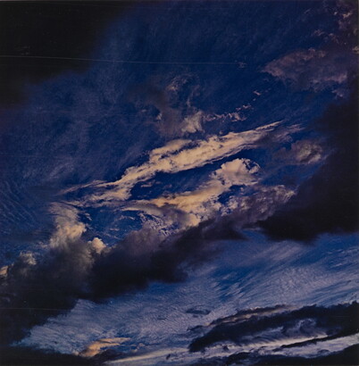 A color photograph of a dark blue sky streaked with dark and light clouds.