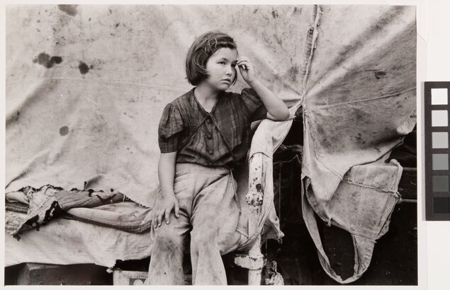 A black-and-white photograph of a young White girl wearing dirty clothes, one hand held up to her forehead, sitting in front of a canvas tent.