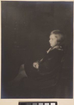 A black-and-white, soft-focus photograph of a young White girl with bobbed hair, sitting in profile.
