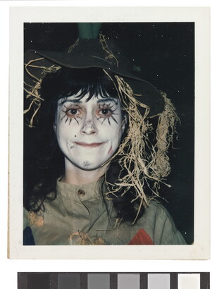 A color portrait of a girl wearing white face paint and dressed as a scarecrow.