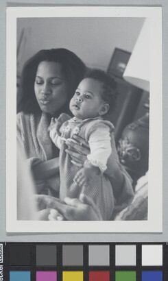 A candid black-and-white photograph of a Black woman holding a baby.