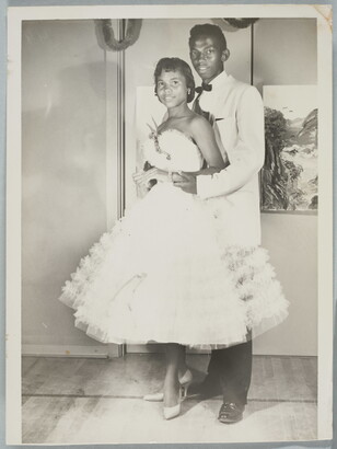 A black-and-white photograph of a Black couple in formal dress at a dance.