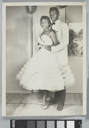 A black-and-white photograph of a Black couple in formal dress at a dance.