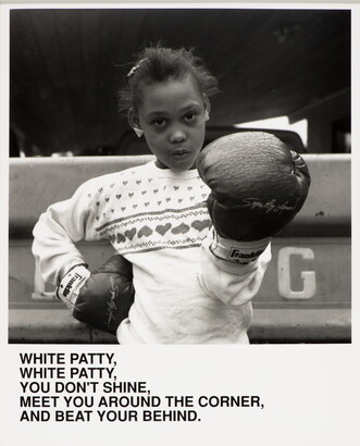 A black-and-white photograph of a Black girl wearing boxing gloves, one hand on her hip the other aimed at the viewer, above text that reads, &quot;White Patty, White Patty, You don&#039;t shine. Meet you around the corner and beat your behind.&quot;
