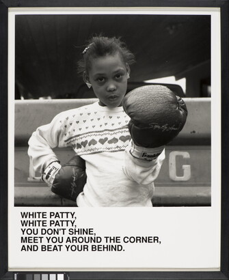 A black-and-white photograph of a Black girl wearing boxing gloves and looking at the camera above text that reads, &quot;White Patty, White Patty, You don&#039;t shine. Meet you around the corner and beat your behind.&quot;