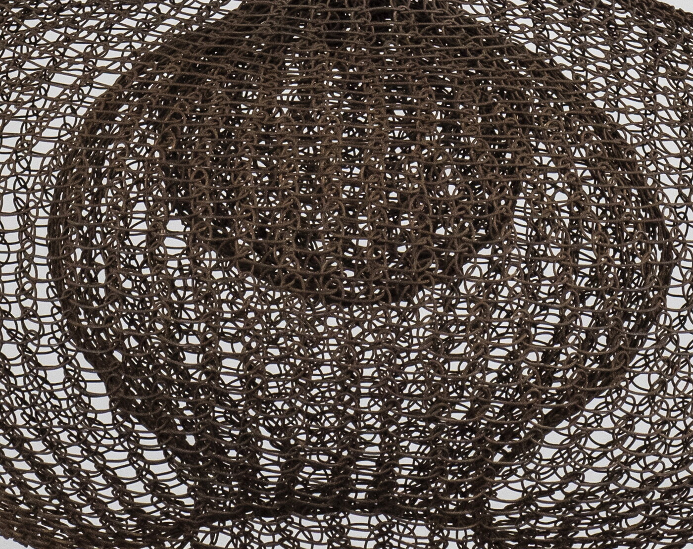 A detail of a hanging sculpture made of woven wire thread that creates three orb like shapes with smaller orbs nested inside each.