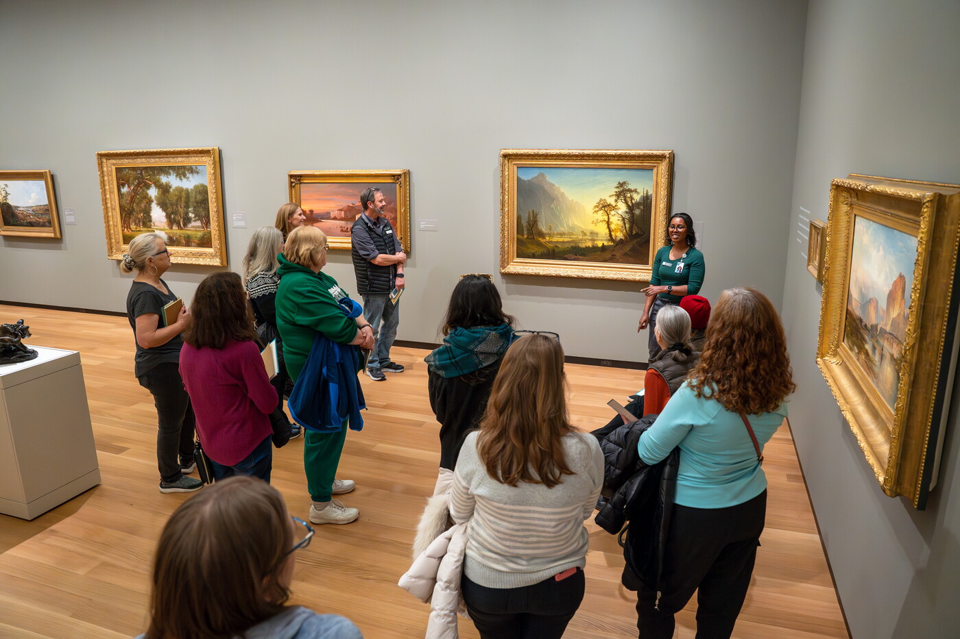 A group of adults stand in a Carter gallery listening to a Museum educator.