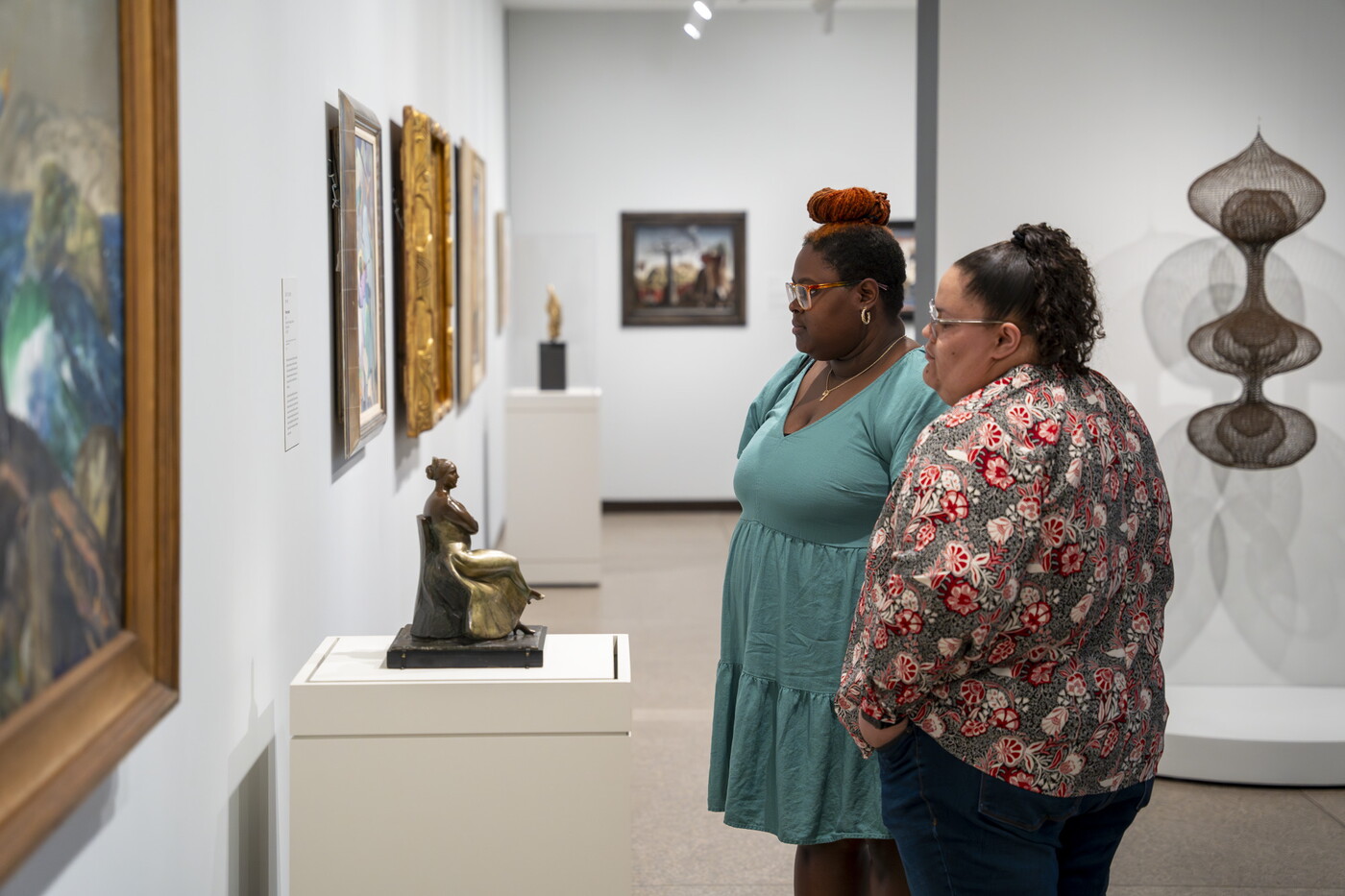 Two women look at artwork on the wall of a Carter gallery.