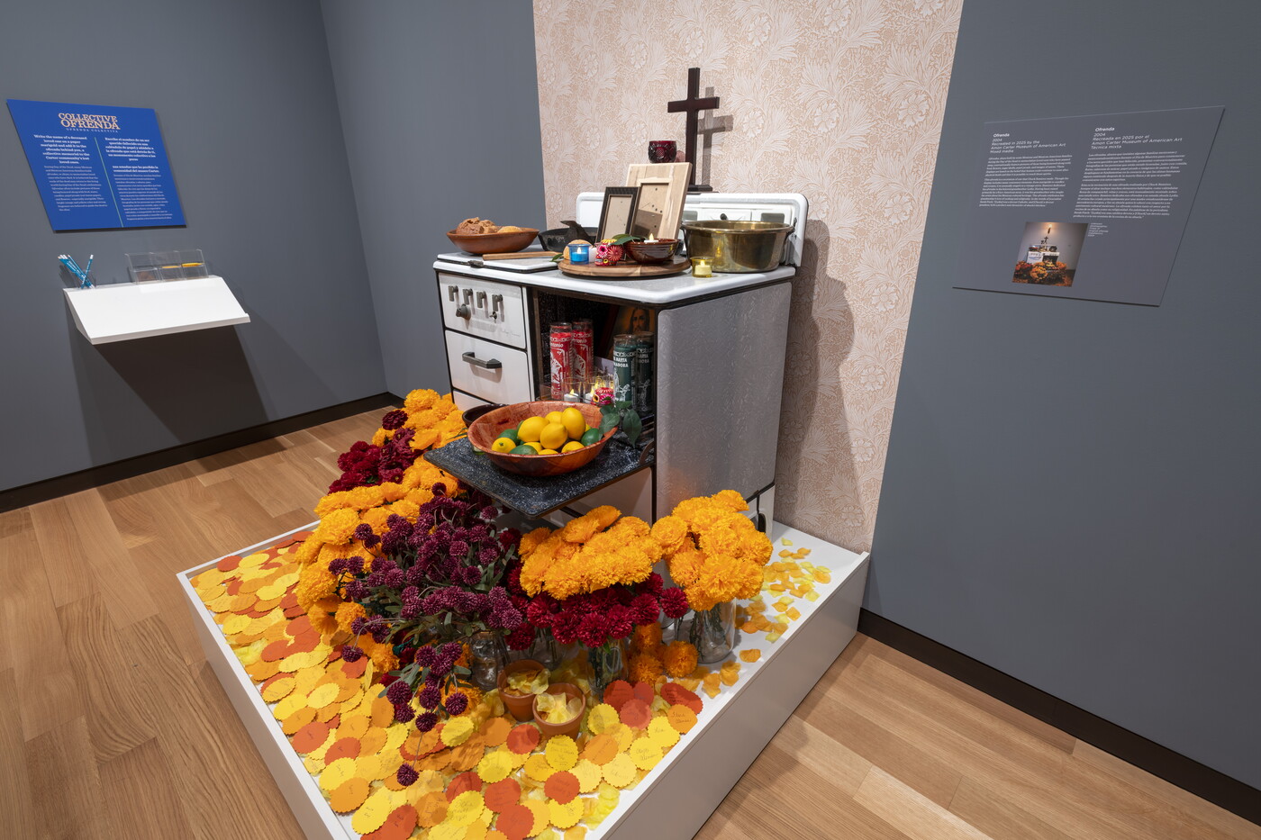 An old-style kitchen stove decorated with memorabilia and paper marigolds sits on a platform in a Carter gallery.
