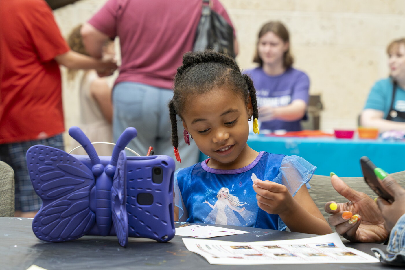 A Black child makes art at a table in the Carter's Atrium.