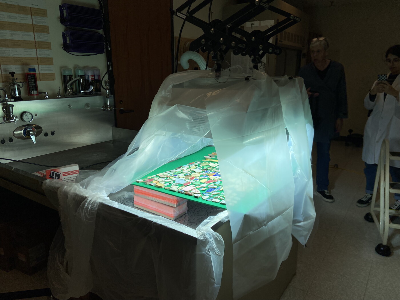 UV lights glow beneath plastic sheets that are draped over a table on which sits the objects being treated.