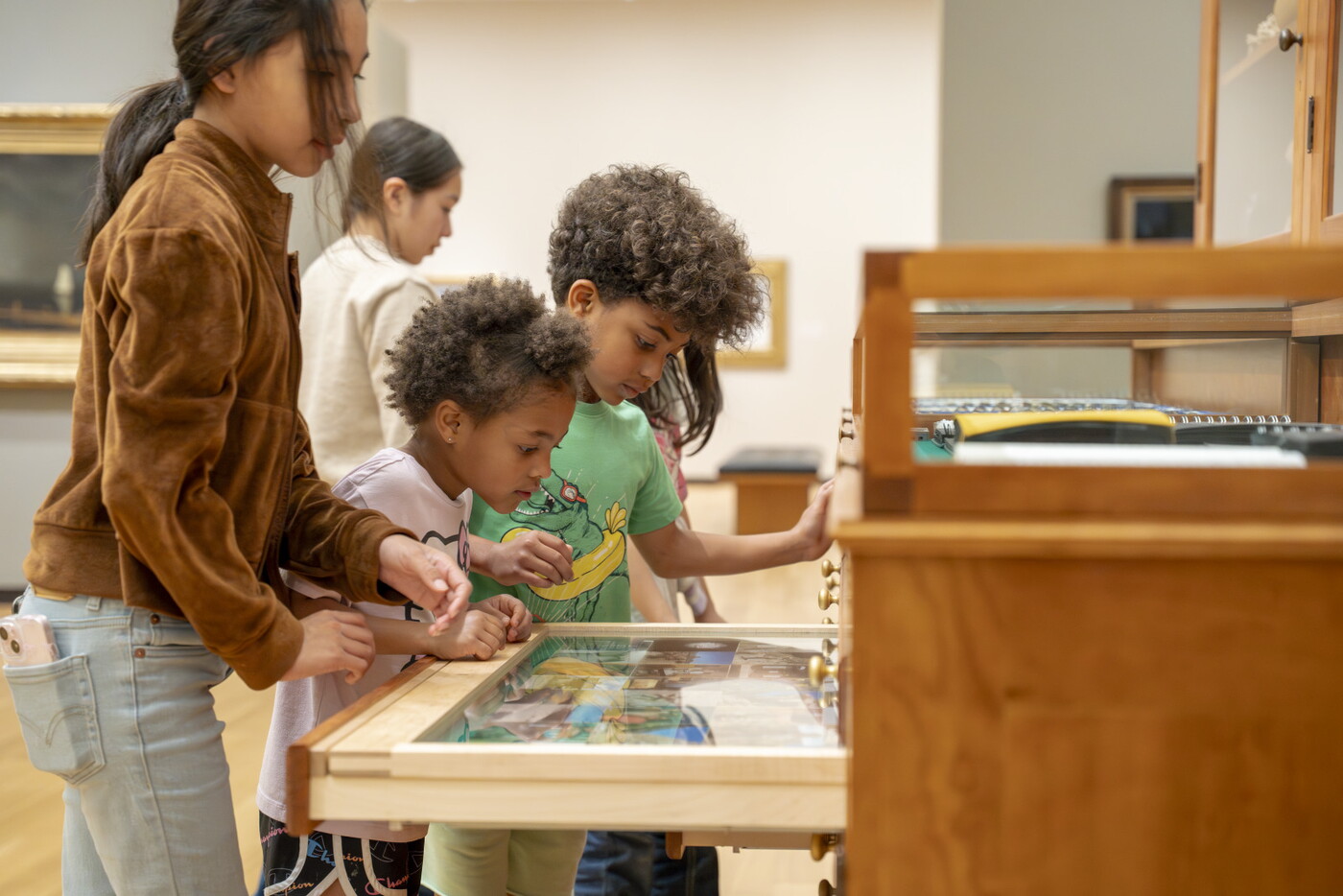 Children of a variety of ages look at the drawers in "The Texas Cabinet" in a Carter gallery.